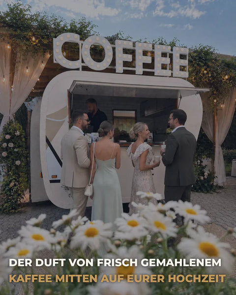 Eleganter Coffee Truck auf einer Hochzeit im Freien mit festlich gekleideten Gästen und frischem Kaffee in romantischer Atmosphäre. Textoverlay Der Duft von frisch gemahlenem Kaffee mitten auf eurer Hochzei