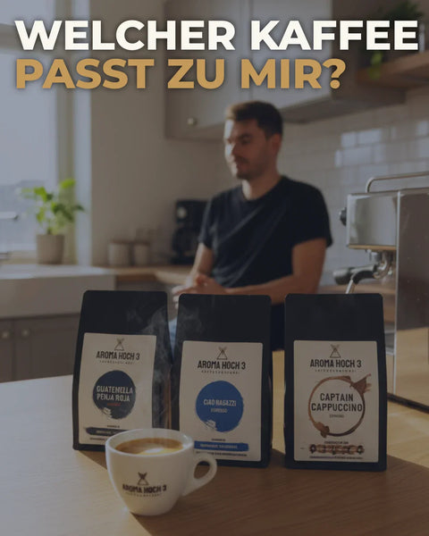 Drei Aroma Hoch 3 Kaffeepackungen und eine Espressotasse stehen auf einem Holztisch in einer warm beleuchteten Küche. Im Hintergrund sitzt eine unscharfe Person neben einer Espressomaschine. Oben steht groß: „Welcher Kaffee passt zu mir?“