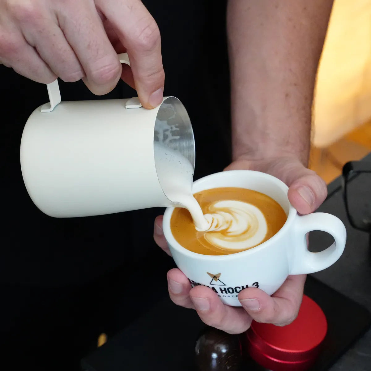 Milchschaum wird als Latte Art in eine Aroma-Hoch-3-Tasse gegossen